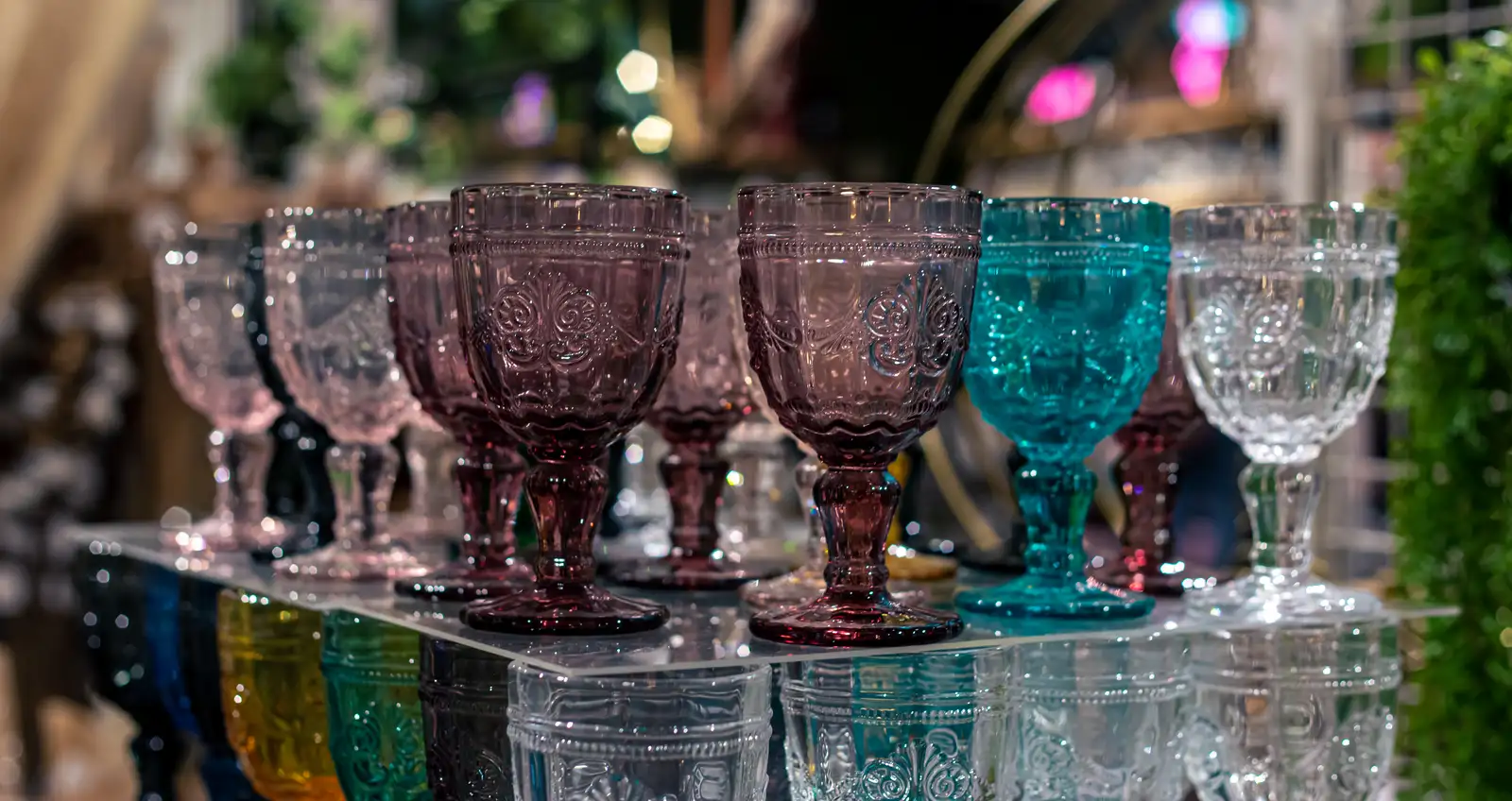 Row of vintage pink, teal, and clear pressed glass goblets