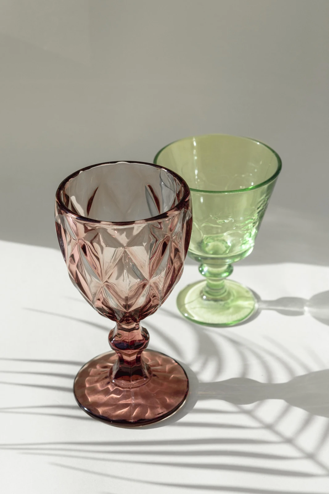 Pink and green pressed glass goblets in sunlight, the classic colors of Depression glass