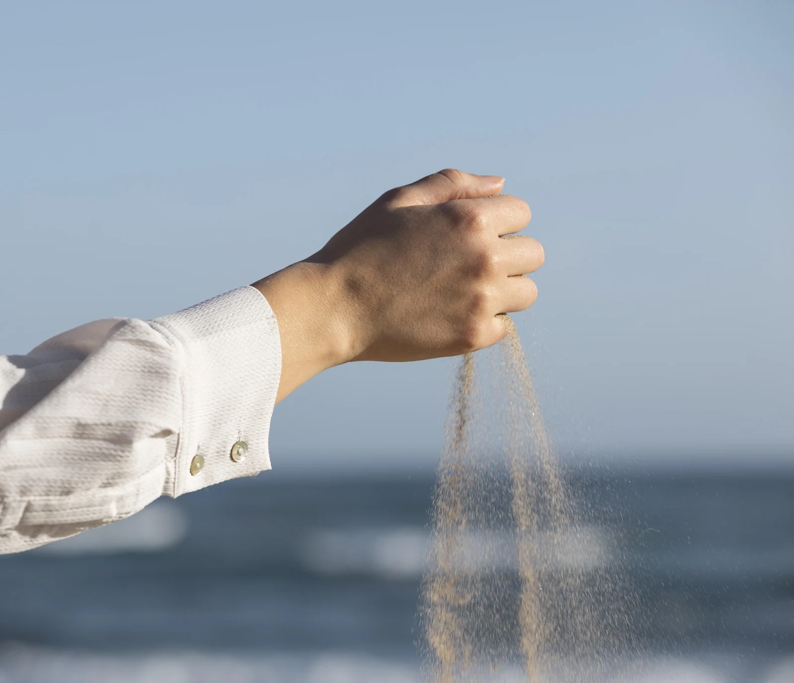 Fine sand pouring from a hand, the silica base of most glass