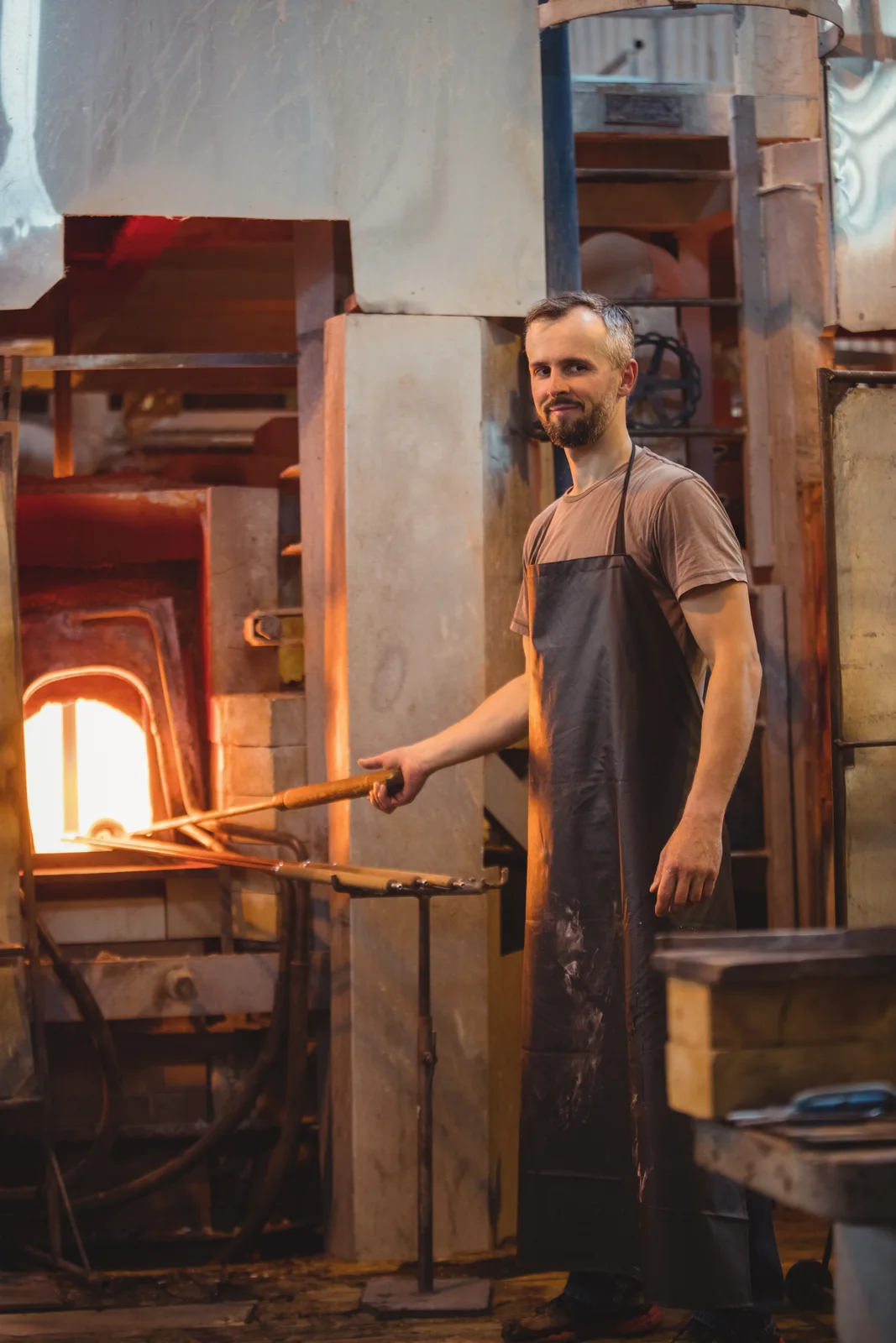 Glassblower heating glass in a glowing furnace, showing what is glass made of and how it melts